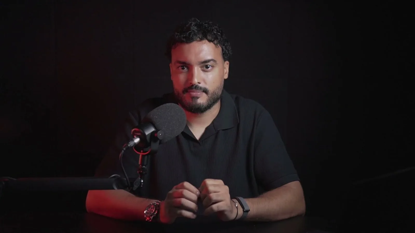 Younes Atlas, fondateur d'Atlas Acquisition, face caméra à son bureau avec micro de studio, présentant la méthode d'acquisition Atlas en vidéo