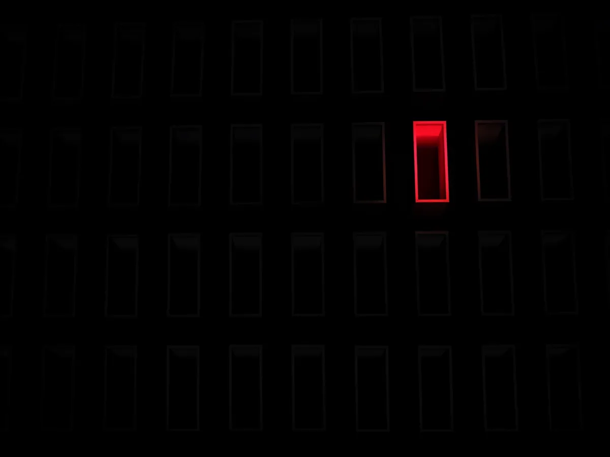 Vue de dessus d'une grille de volumes sombres identiques dont un seul est allumé en rouge : un choix délibéré parmi beaucoup de dossiers possibles.